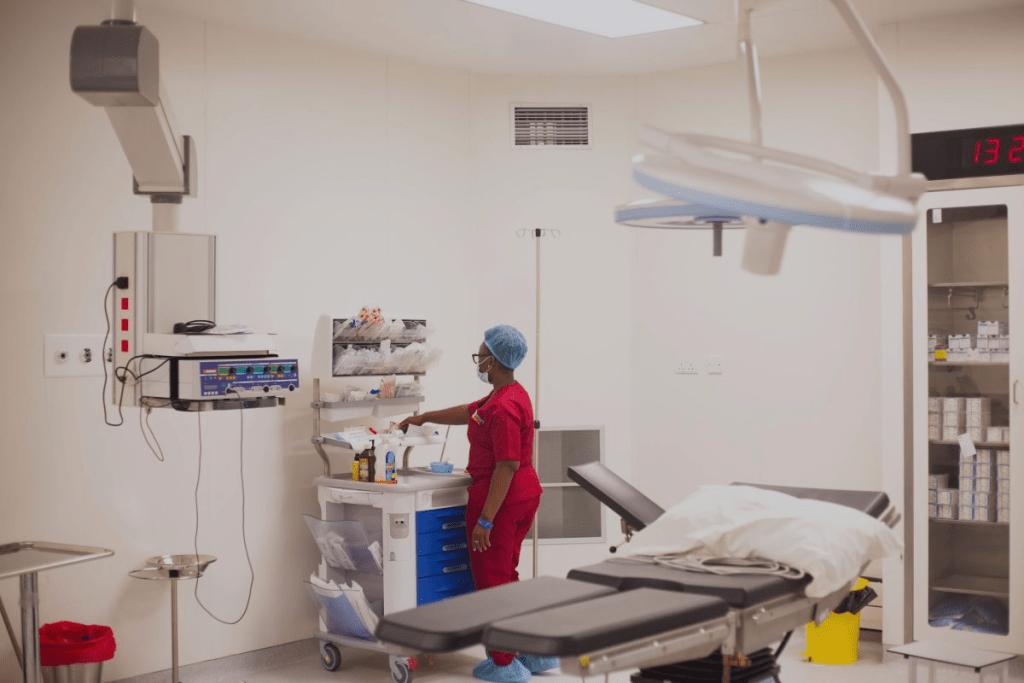 Healthcare worker preparing supplies beside an operating table in a clinic