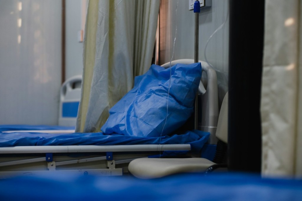 Hospital bed with blue sheets and pillow